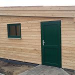 modernes Pultdachhaus aus Lärche mit grüner Holztür